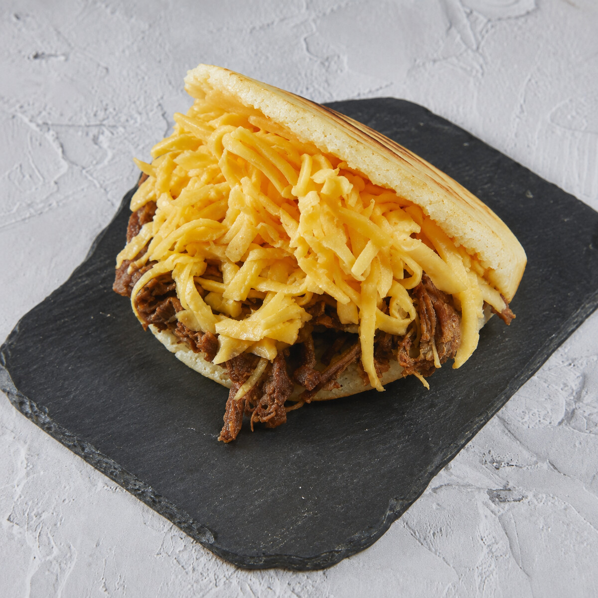 Arepa peluda, carne mechada + queso cheddar o blanco